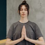 A woman meditating indoors with eyes closed, focusing on mindfulness and relaxation.