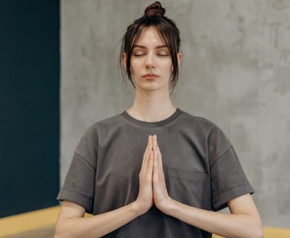 A woman meditating indoors with eyes closed, focusing on mindfulness and relaxation.