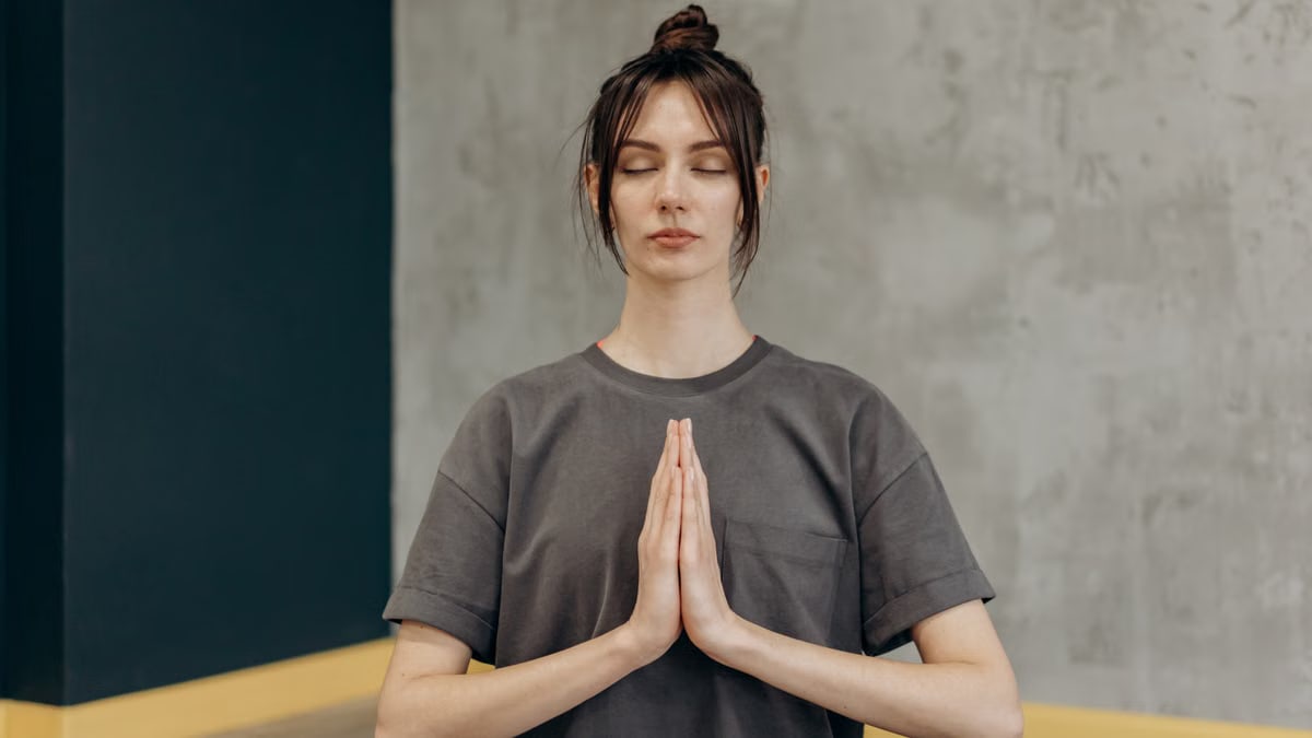 A woman meditating indoors with eyes closed, focusing on mindfulness and relaxation.