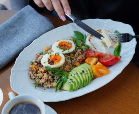 A delicious and healthy breakfast featuring avocado, eggs, and coffee served on a wooden table.